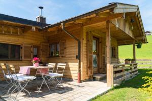 Cette cabane en bois dispose d'une terrasse avec une table et des chaises. dans l'établissement Alpenchalet Sachrang, à Sachrang