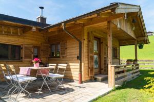 eine Holzhütte mit einem Tisch und Stühlen auf einer Terrasse in der Unterkunft Alpenchalet Sachrang in Sachrang