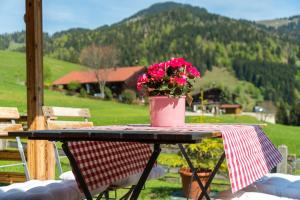 una mesa con una maceta de flores rosas. en Alpenchalet Sachrang, en Sachrang