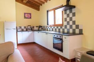 uma cozinha com armários brancos e um forno com placa de fogão em La Casa Lemuria - Süd-Toscana em Zancona