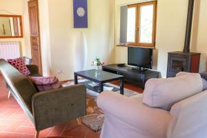 uma sala de estar com duas cadeiras e uma televisão em La Casa Lemuria - Süd-Toscana em Zancona