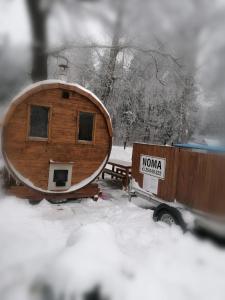 Apartamenti pie Lienes في Gardene: كابينة خشبية صغيرة في الثلج بجانب شاحنة