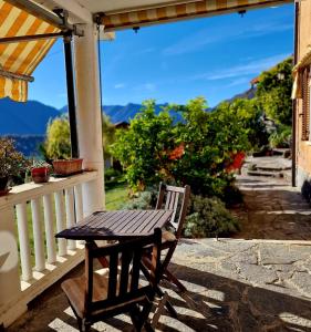 a wooden table and chair on a porch with a view at Casa Melina 2 in Tremezzo