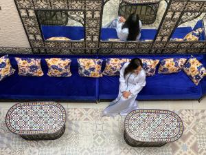 a woman is standing next to a blue couch at Riad Najiba in Rabat