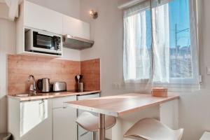 uma cozinha branca com um balcão e uma janela em Le 101 - Studio avec mezzanine à 20 min à pied Gare St-Charles em Marselha