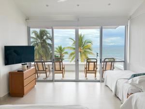 a bedroom with a tv and a balcony with the ocean at Quinta Del Mar El francés in Tolú