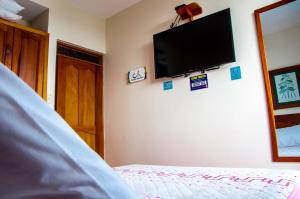 1 dormitorio con 1 cama y TV de pantalla plana en la pared en Hotel Camino Nacional Salento, en Salento