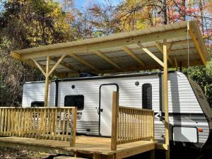 a trailer with awning on a deck with a porch at Daffodil Dream Camper with Hot Tub - Movie Screen - Fire Pit - BBQ in Jonesville