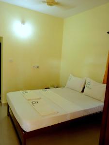 1 cama con sábanas blancas y almohadas en una habitación en La Mirban, en Varkala