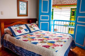 a bedroom with a bed with a quilt on it at Hotel Camino Nacional Salento in Salento