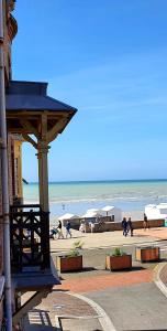 een strand met een gebouw en mensen die op het strand lopen bij Villa Antonio - Bow-window balcon vue mer Appartement 1 chambre in Mers-les-Bains