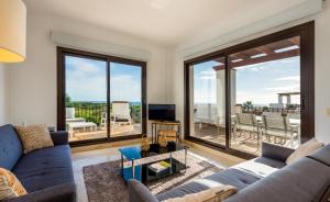 uma sala de estar com um sofá azul e janelas grandes em 2113-Beautiful 2 beds apt with seaview em La Alcaidesa