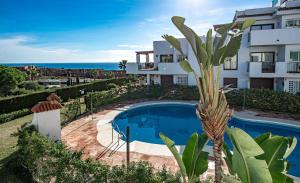 uma villa com uma piscina e uma palmeira em 2113-Beautiful 2 beds apt with seaview em La Alcaidesa