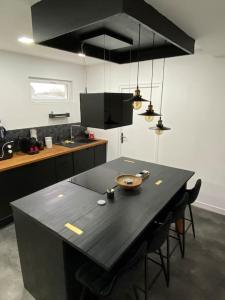 a kitchen with a black table and some lights at Makeda Love & Jacuzzi in Neuville-Saint-Amand