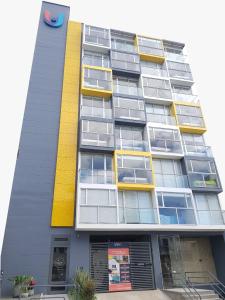 ein hohes Gebäude mit gelb und grau in der Unterkunft Ulivin Apartaestudios Manizales in Manizales
