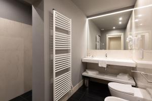 bagno con servizi igienici, lavandino e specchio di Palazzo Liberati Apartments a Parma