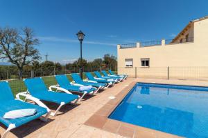 una fila de sillas azules junto a una piscina en Can Bugantó amplia casa con piscina y jardín en Llambillas