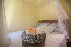 a bed with a canopy and a basket with towels at Pousada Deus mim Deu in Caraíva