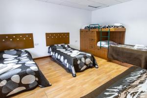 two beds in a room with wooden floors at Can Bugantó amplia casa con piscina y jardín in Llambillas