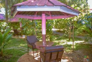 Beach View Hotel - Kisumu في كيزيمو: طاولة و كرسيين تحت مظلة وردية