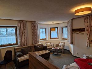 a living room with a couch and chairs and windows at Haus Haas in Lermoos