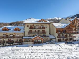 un hotel en la nieve con edificios cubiertos de nieve en Duplex rénové - 2 chambres 7 personnes vue pistes en Les Orres