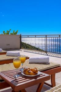 une table avec une assiette de nourriture et deux verres de jus d'orange dans l'établissement Apartments Mrkan, à Cavtat