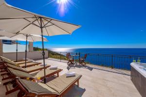 d'une terrasse avec des chaises et des parasols donnant sur l'océan. dans l'établissement Apartments Mrkan, à Cavtat
