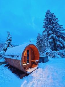 una cabaña de madera en la nieve con un árbol en Zarabie Residence, en Myślenice