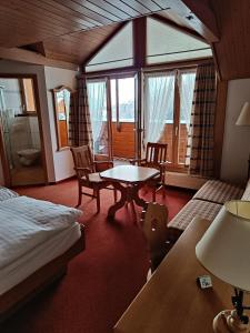 Schlafzimmer mit einem Bett, einem Tisch und Stühlen in der Unterkunft Hotel Adler in Sigriswil