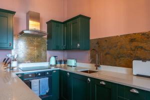 a kitchen with green cabinets and a sink at Stylish Beachfront Apartment, Sweeping Ocean Views and Luxury Touches in Herne Bay