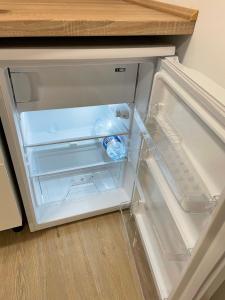 an empty refrigerator with a bottle of water in it at AA Apartman in Kaposvár