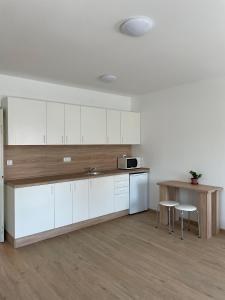 eine Küche mit weißen Schränken sowie einem Tisch und Stühlen in der Unterkunft AA Apartman in Kaposvár