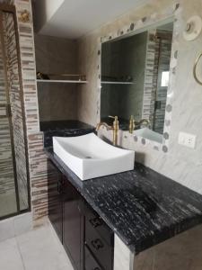 y baño con lavabo blanco y espejo. en Departamento vacacional, en Guayaquil