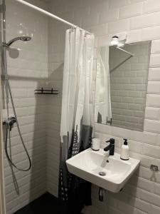 biała łazienka z umywalką i prysznicem w obiekcie Mere Puiestee Apartment w Tallinnie