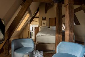 a attic room with a bed and two chairs at Cour des Vosges - Evok Collection in Paris
