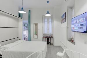Dieses weiße Zimmer verfügt über ein Bett und einen Flachbild-TV. in der Unterkunft Santi Quattro Apartment & Rooms - Colosseo in Rom