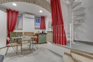 eine Küche mit roten Vorhängen und einem Tisch mit Stühlen in der Unterkunft Santi Quattro Apartment & Rooms - Colosseo in Rom