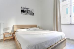 Schlafzimmer mit einem Bett mit weißer Bettwäsche und einem Fenster in der Unterkunft Santi Quattro Apartment & Rooms - Colosseo in Rom