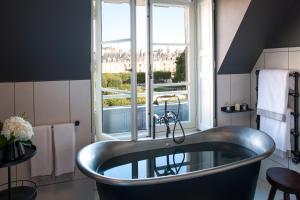 a bathroom with a tub in front of a window at Cour des Vosges - Evok Collection in Paris