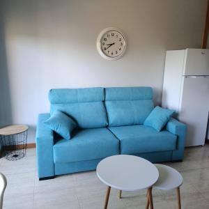 a blue couch in a living room with a clock on the wall at Apartamento Samil Primera Línea de Playa 2F in Vigo