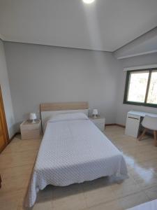 a bedroom with a white bed and a window at Apartamento Samil Primera Línea de Playa 2F in Vigo