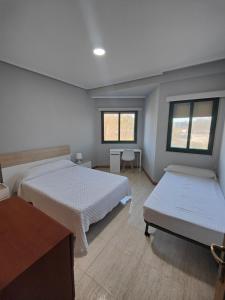 a bedroom with two beds and a table and two windows at Apartamento Samil Primera Línea de Playa 2F in Vigo