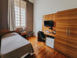 Schlafzimmer mit einem Bett und einem Schreibtisch mit einem TV in der Unterkunft NHM Hotel in Araraquara