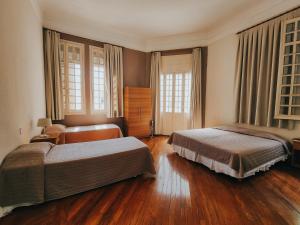1 dormitorio con 2 camas, suelo de madera y ventanas en NHM Hotel, en Araraquara