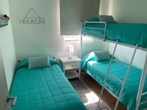 1 dormitorio con 2 literas y mesa con lámpara en Hermoso departamento en Papudo con Vista, en Papudo