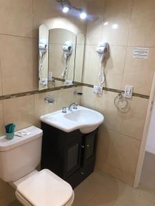 Un baño con lavabo, inodoro y espejo. en Departamento Mailin, en Puerto Madryn