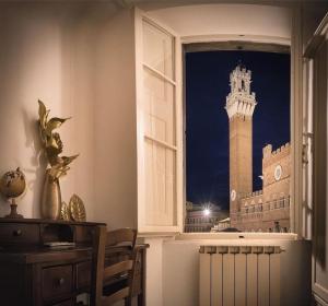 uma janela com vista para um edifício com uma torre de relógio em Residenza d'Epoca " Il Campo" by FrancigenaApartments em Siena