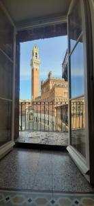 a view of a clock tower from an open window at Residenza d'Epoca " Il Campo" by FrancigenaApartments in Siena