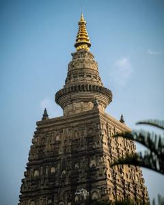 una torre alta con una cima d'oro sopra. di Nilam Guest House a Bodh Gaya